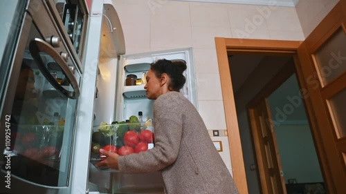 Woman placing fresh vegetables in refrigerator for healthy meal preparation