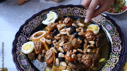 Traditional Moroccan Meat with Prunes, Nuts, and Boiled Eggs in Ornate Peacock Platter – Authentic North African Cuisine for Festive Occasions  
