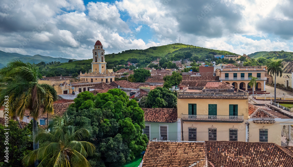 Picturesque view of Trinidad, Cuba, showcasing colonial architecture, lush greenery, and historic charm under a vibrant blue sky with scattered clouds
