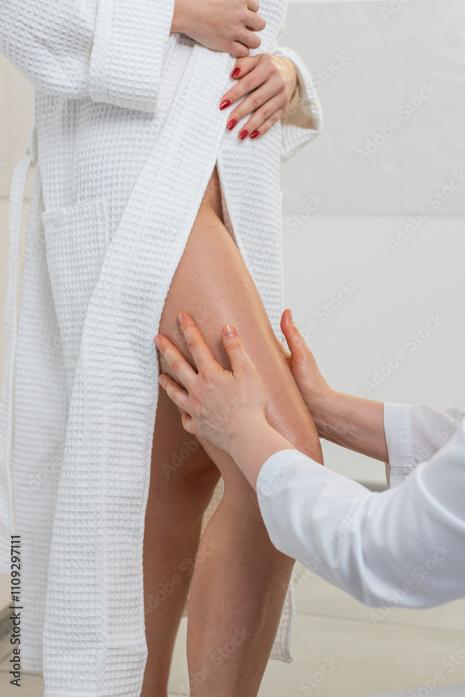 Cosmetologist therapist doctor making woman relaxing spa anti-cellulite legs treatment massage with smooth hands movements. Slimming, body shaping. Client in physical beautician cosmetology session Cosmetologist therapist doctor making woman relaxing spa anti-cellulite legs treatment massage with smooth hands movements. Slimming, body shaping. Client in physical beautician cosmetology session