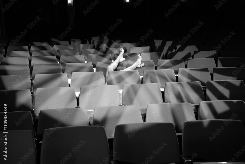 Naklejka premium sie streckt ihre beine über die leeren Ränge im Theater