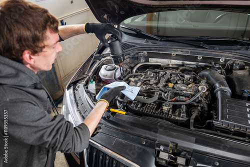 Mechanic wearing gloves inspecting and cleaning the oil filter of a car's engine in a workshop, showcasing vehicle maintenance concept	
 photo