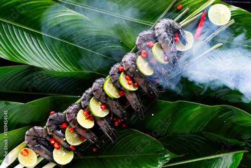 Sizzling tiger shrimp marinated with spices lie elegantly on lush banana leaves, garnished with lime and chili for a vibrant Asian culinary delight. photo