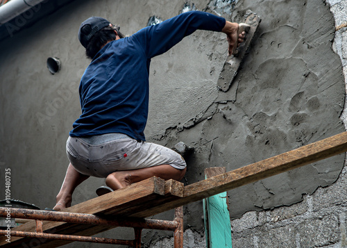 Baubau, Indonesia, June 15 2024 - A craftsman who is renovating a wall photo