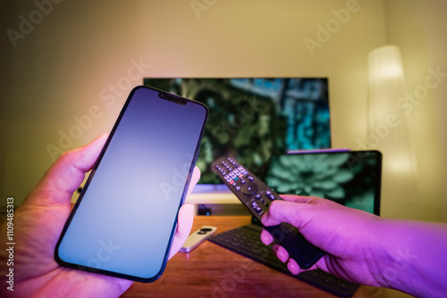 hand holding smartphone TV remote control laptop blank screen mockup