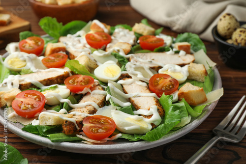 Delicious Caesar salad with chicken on wooden table, closeup