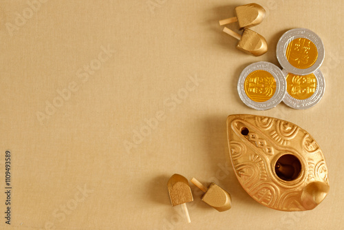 Top view of Jewish holiday Hanukkah with oil jug, wooden dreidels and chocolate coins. Golden banner photo