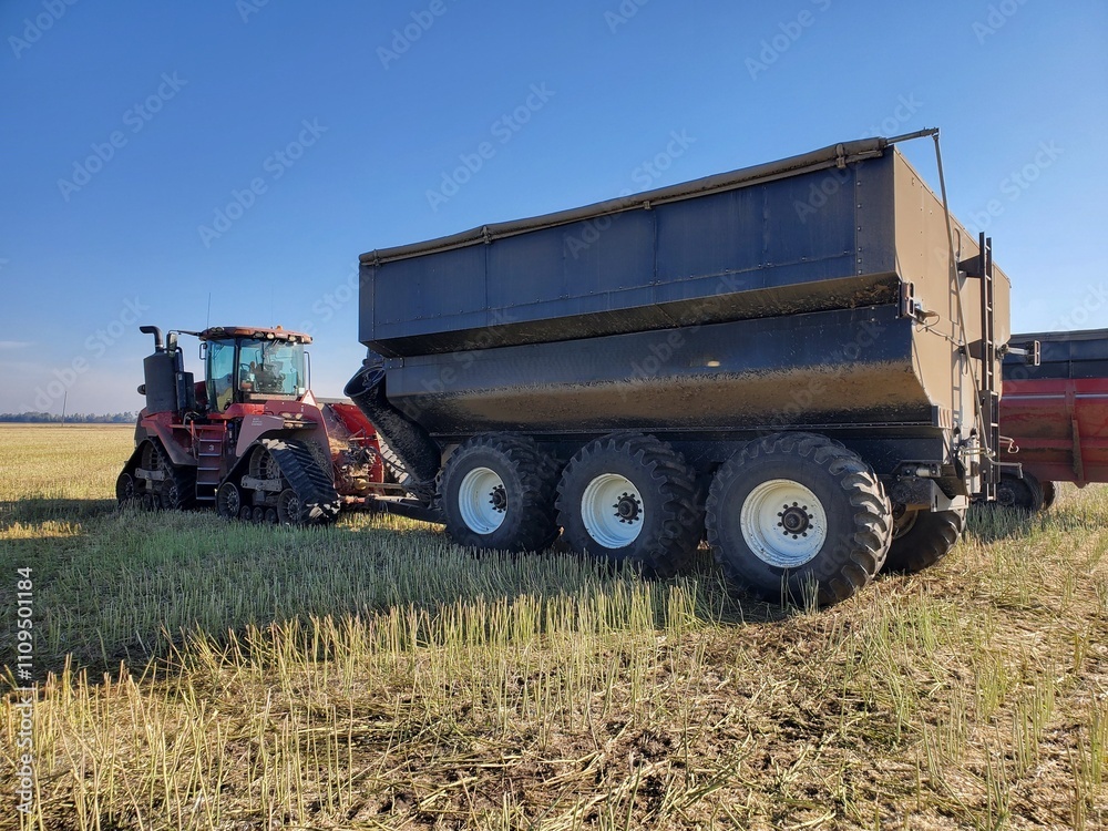 A large grain cart being pulled by a large quad track tractor. A large grain cart being pulled by a large quad track tractor.