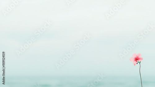   A pink flower resting atop a sandy shore, beside the blue sea and clear sky above