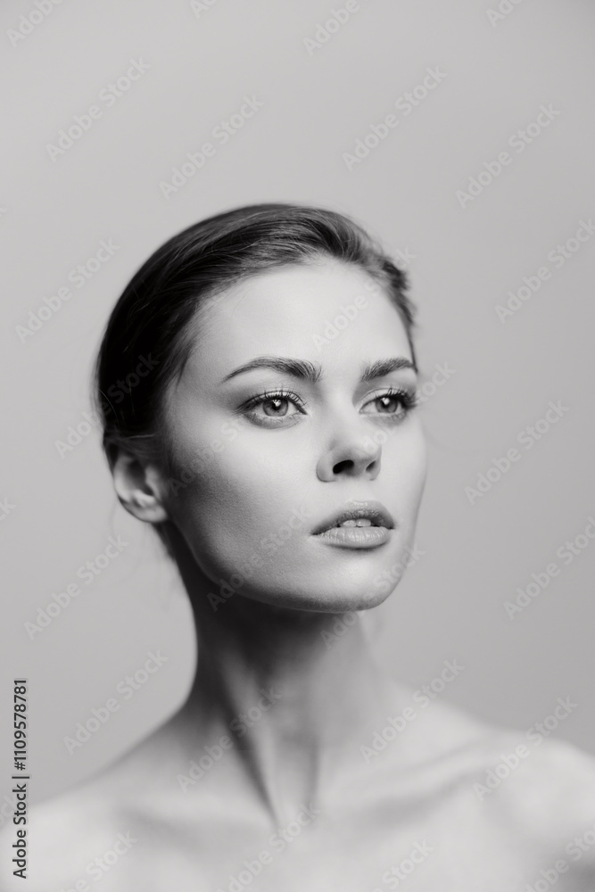 Fototapeta premium Young woman with a graceful pose, showcasing elegance and poise against a soft gray background. Capturing beauty and confidence through minimalistic composition.