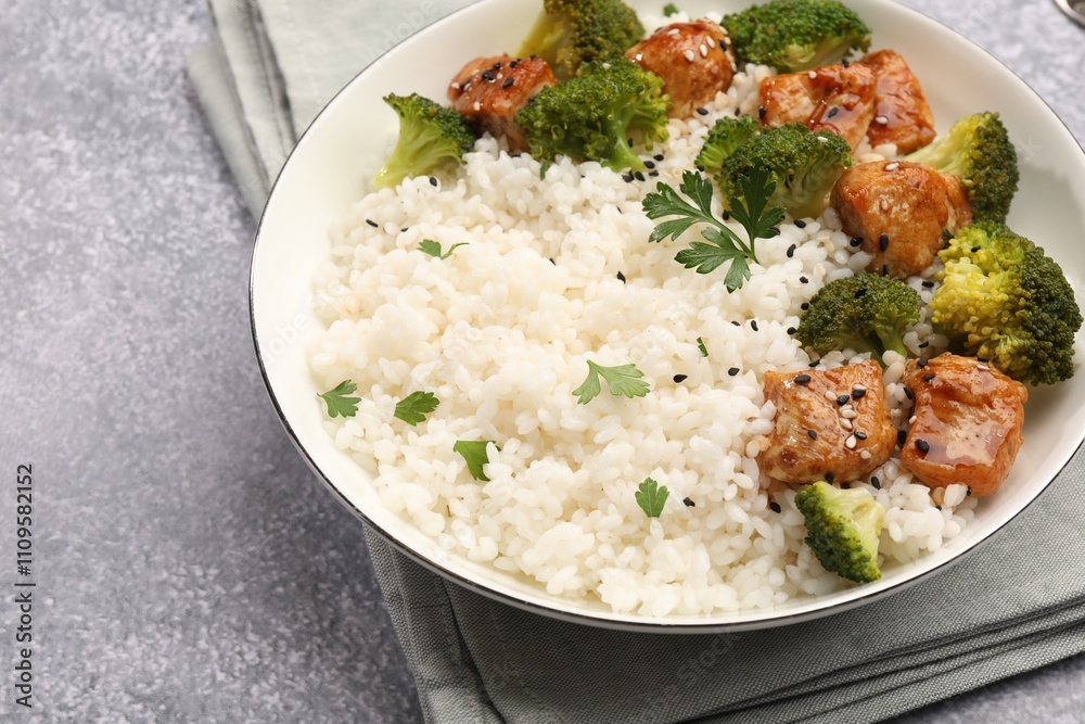 Tasty rice with broccoli, chicken and parsley on grey table, closeup Tasty rice with broccoli, chicken and parsley on grey table, closeup