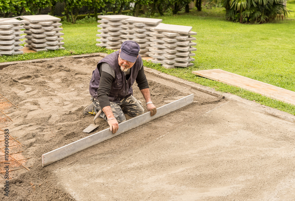 A worker is preparing the sand and cement for placing the concrete floor slabs, including groundwork and exterior paving. A worker is preparing the sand and cement for placing the concrete floor slabs, including groundwork and exterior paving.