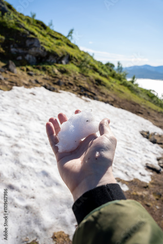 Male holding snow in hand in summer at Mount Storsteinen in Tromso, Norway photo