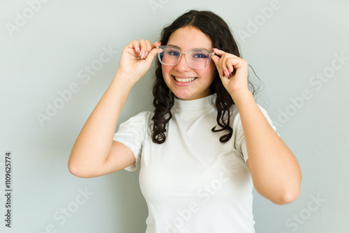 Beautiful latin teenager girl adjusting her new eyeglasses and smiling, happy with her improved eyesight