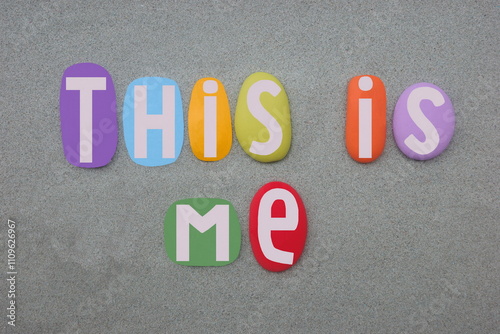 This is me, creative slogan composed with multi colored stone letters over green sand