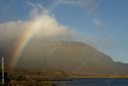 A vibrant rainbow arcs over the mountains in Iceland, adding color to the landscape