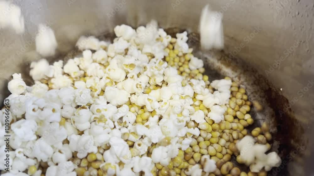 Close-up of popcorn being made, with kernels popping into fluffy pieces. Captured during the cooking process in a pot or popcorn machine, showing motion, heat, and transformation. A fun and tasty