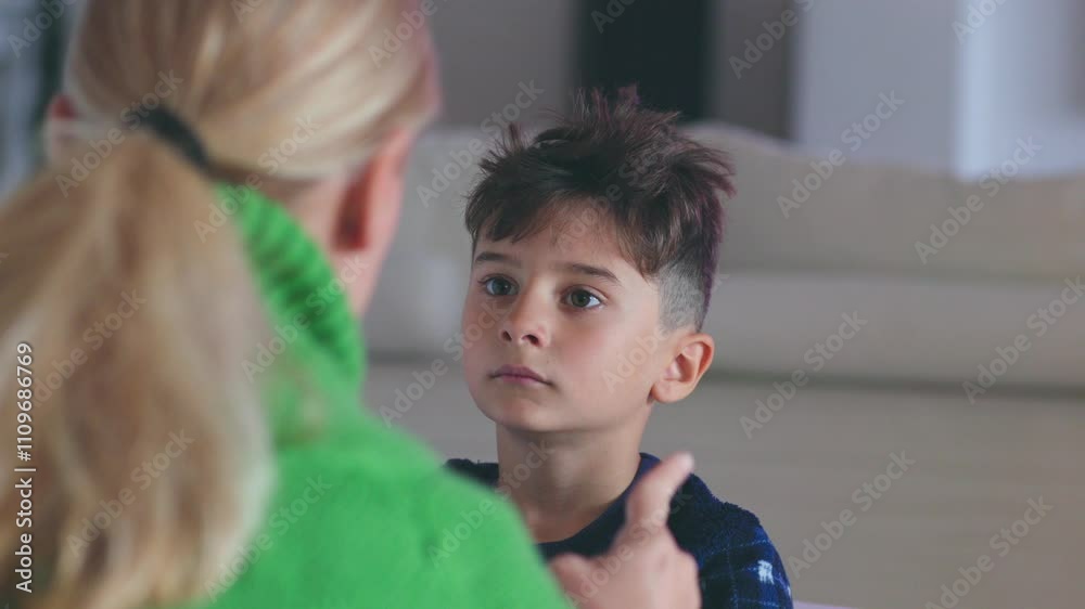 A mother firmly addressing her rebellious son, offering guidance and advice on proper behavior. They are seated in the living room during a serious moment of discipline and learning. A mother firmly addressing her rebellious son, offering guidance and advice on proper behavior. They are seated in the living room during a serious moment of discipline and learning.