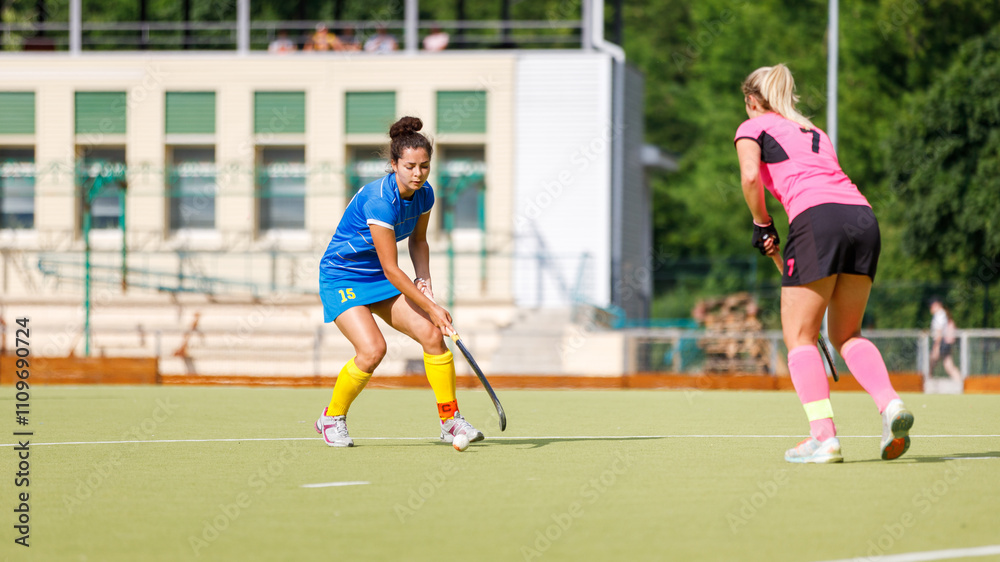 Two young female athletes compete in intense field hockey match during sunny day Two young female athletes compete in intense field hockey match during sunny day