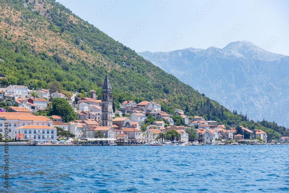 Fototapeta premium Coastal town nestled between mountains and water in summer sunlight