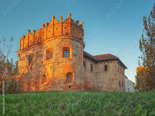 view from door point to grass meadow and crown shape brick tower of old castle in sunset time photo