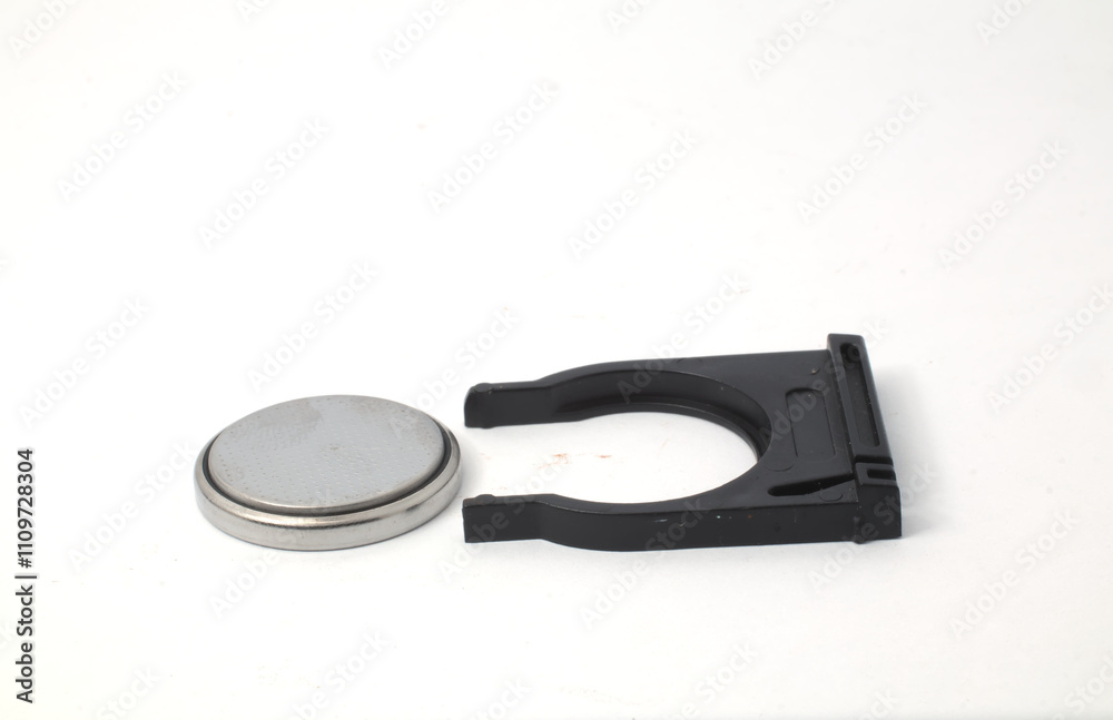 A button battery and a light remote control tray on a white background. Used to power the light control remote. A button battery and a light remote control tray on a white background. Used to power the light control remote.