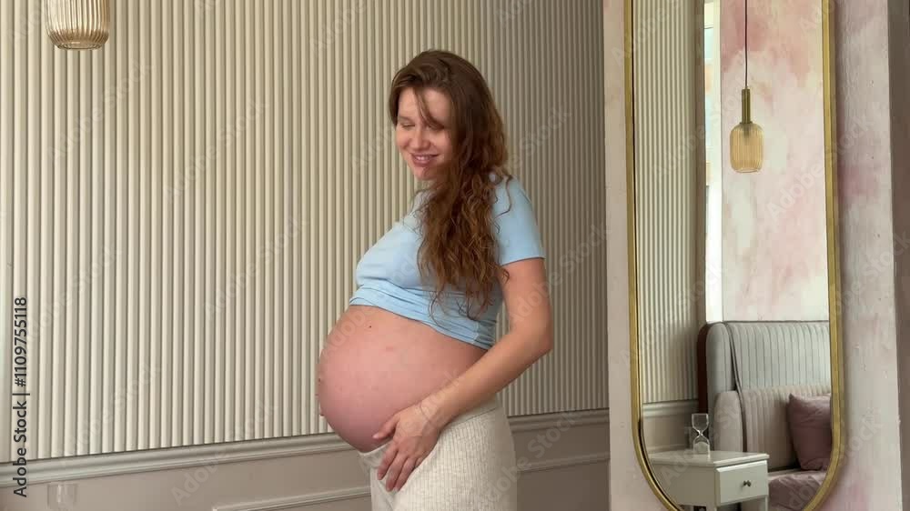 beautiful pregnant woman wakes up and pulls up in the morning in bed in the bedroom and strokes her belly, 3 trimester