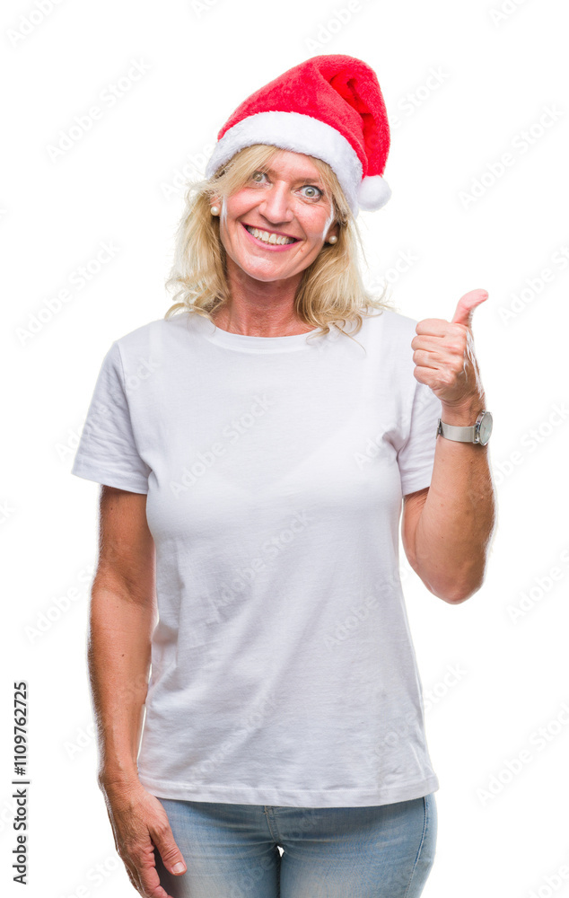 Middle age blonde woman wearing christmas hat over isolated background doing happy thumbs up gesture with hand. Approving expression looking at the camera with showing success. Middle age blonde woman wearing christmas hat over isolated background doing happy thumbs up gesture with hand. Approving expression looking at the camera with showing success.