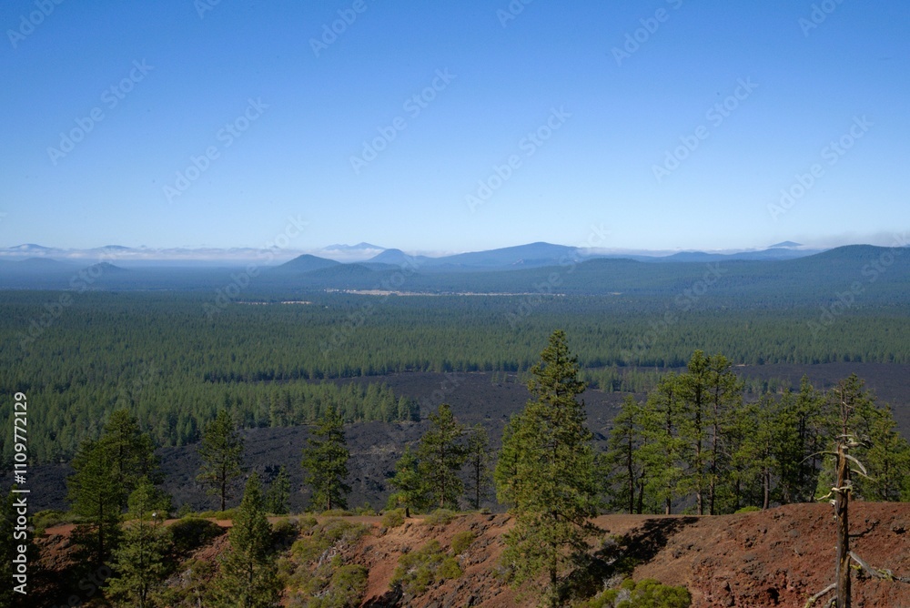 View of surrounding Cascade Mountain Range in the background as seen from the top of a lava butte, with the massive blanket of lava still covering the landscape. View of surrounding Cascade Mountain Range in the background as seen from the top of a lava butte, with the massive blanket of lava still covering the landscape.