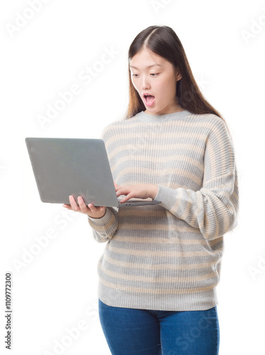 Young Chinese woman over isolated background using computer laptop scared in shock with a surprise face, afraid and excited with fear expression