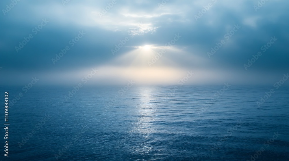Sunbeams pierce through misty clouds over calm ocean. Sunbeams pierce through misty clouds over calm ocean.