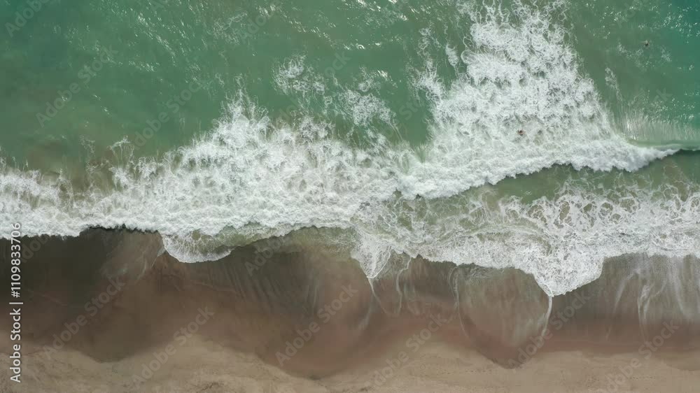 Aerial of waves crashing and surfer riding wave