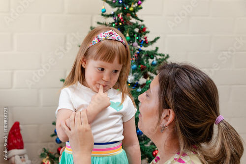 mamá interactuando con su pequeña hija en un ambiente de navidad photo