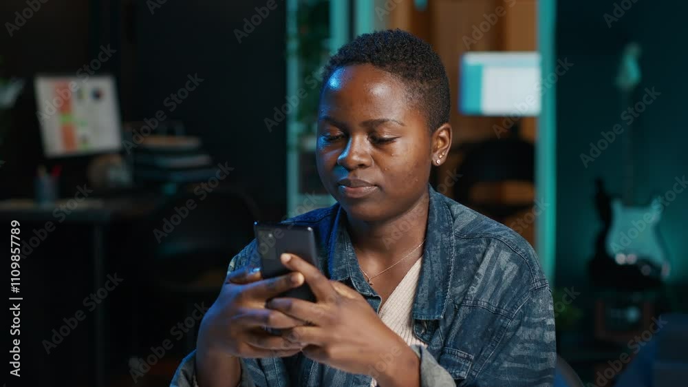 Jolly woman relaxing at home sitting at office desk, texting friends on smartphone in front of laptop. Cheerful freelancer taking break to chat with mates online using phone in living room, camera A Jolly woman relaxing at home sitting at office desk, texting friends on smartphone in front of laptop. Cheerful freelancer taking break to chat with mates online using phone in living room, camera A