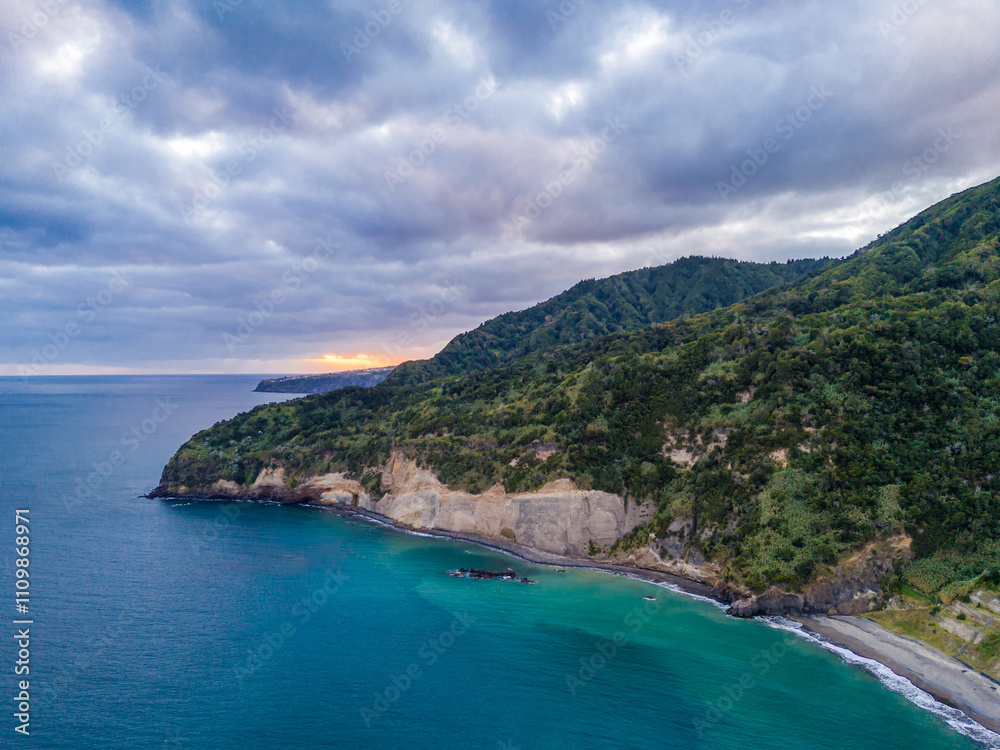 Fototapeta premium Aerial drone view of Praia do Fogo with volcanic black sand beach in Ribeira Quente. Landscape of Sao Miguel coastline with green mountains in Azores