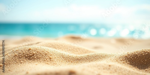 A Close-Up of Smooth, Golden Sand Dunes With the Blurred Image of a Turquoise Ocean in the Background
