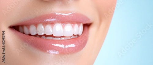 A close-up of a smiling mouth showcasing bright, white teeth and glossy lips against a soft blue background.