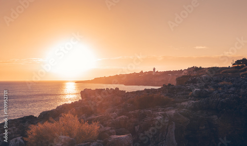 The setting sun casts a warm golden glow over the rugged coastline of cascais, portugal, creating a breathtaking scene of natural beauty and tranquility