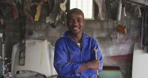 Obraz na płótnie Portrait of a happy African male panel beater in a township workshop, holding a