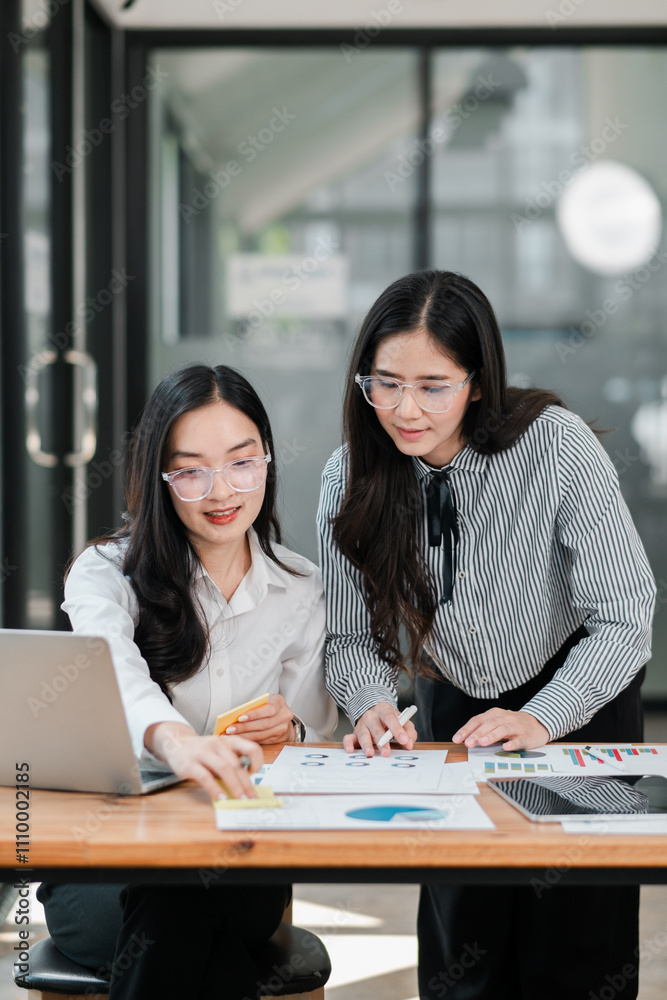 Two professional women working together on a project in a contemporary office environment, focusing on charts and data. Two professional women working together on a project in a contemporary office environment, focusing on charts and data.
