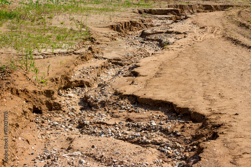 Gully on sandy soil exposing alluvial rock deposits
