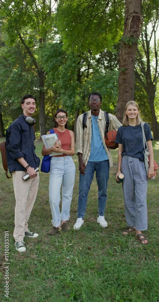 A group of young people with briefcases on their shoulders are smiling at the camera while standing in a city park. Summer day A group of young people with briefcases on their shoulders are smiling at the camera while standing in a city park. Summer day