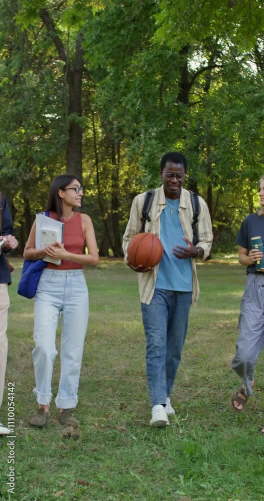 A group of students is walking through the park. They are talking and smiling. Summer day A group of students is walking through the park. They are talking and smiling. Summer day