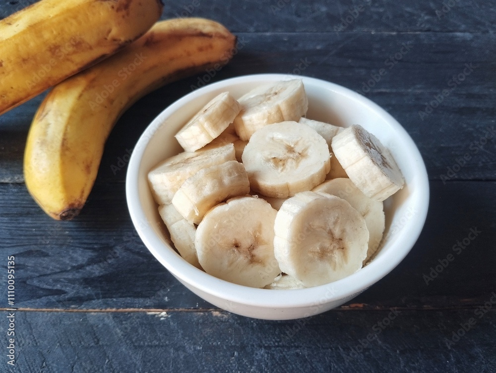 Slices of fresh banana in a bowl on wooden table Slices of fresh banana in a bowl on wooden table