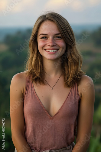 Woman with a serene smile, standing in front of a scenic landscape