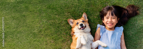 犬と一緒に芝生に寝転んでいるアジア人の幼い少女。（A young Asian girl is lying on the grass with her dog.）
 photo