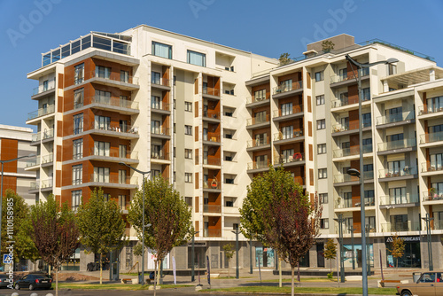 A large apartment building with a green tree in front of it