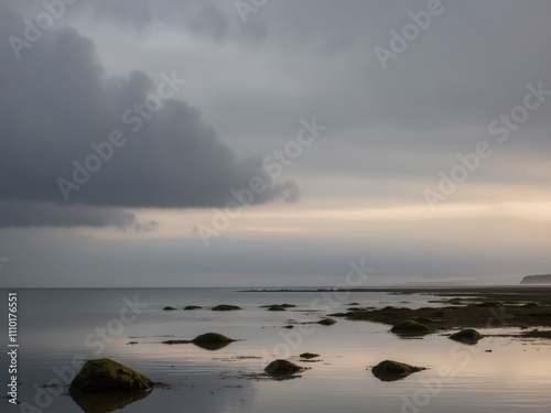 moody seascape at low tide with dark clouds and calm water reflecting the early morning light. photo