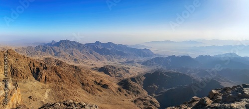 Panoramic mountain landscape from a summit showcasing vast valleys and rugged peaks under a clear blue sky photo