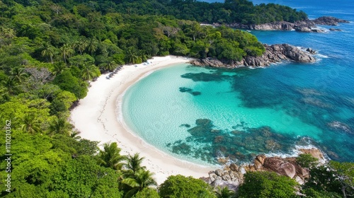 Aerial view of tranquil turquoise beach surrounded by lush greenery and rocky coastline on a sunny day